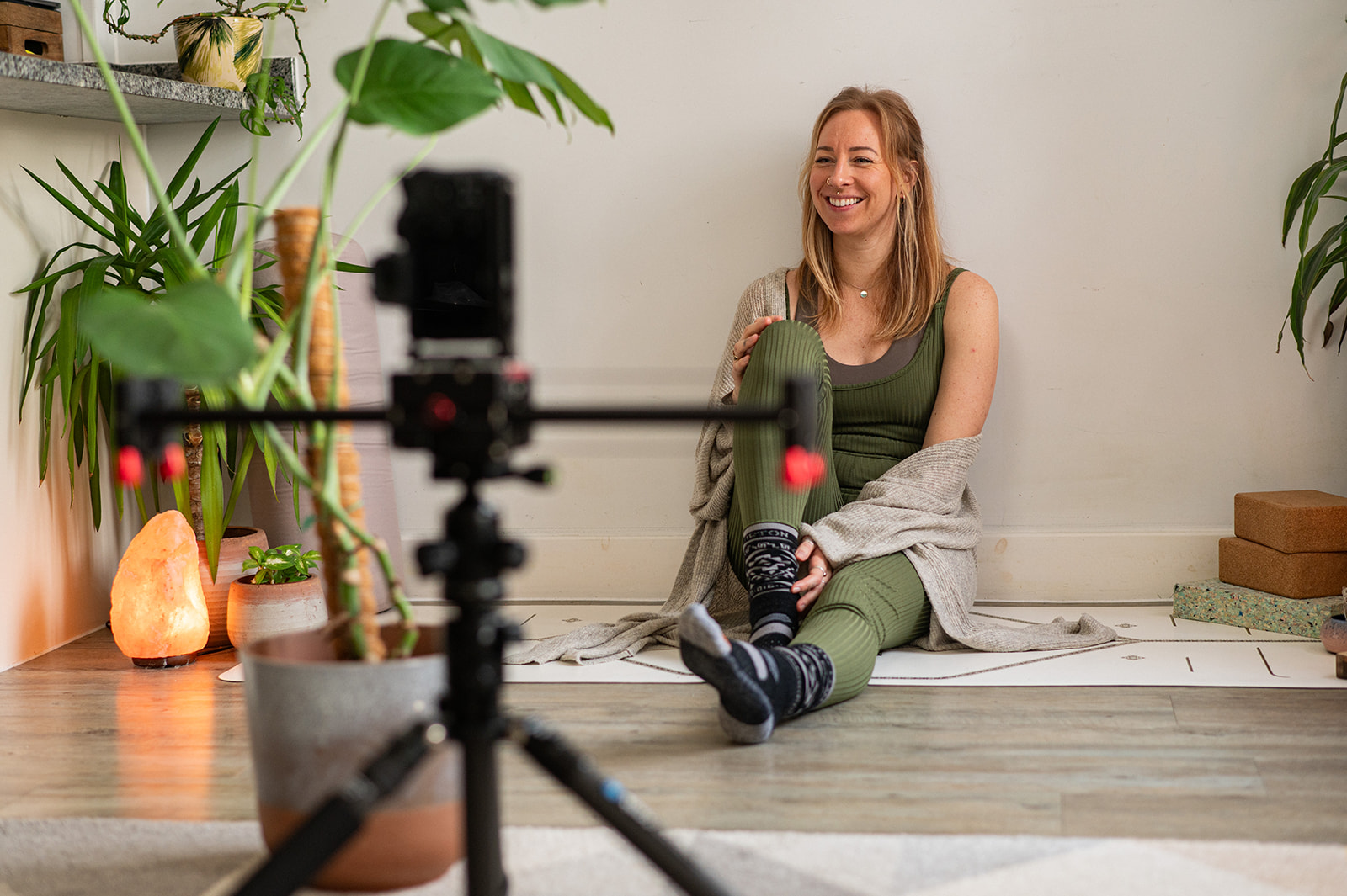 Lottie smiling on a yoga mat in front of a camera on a tripod