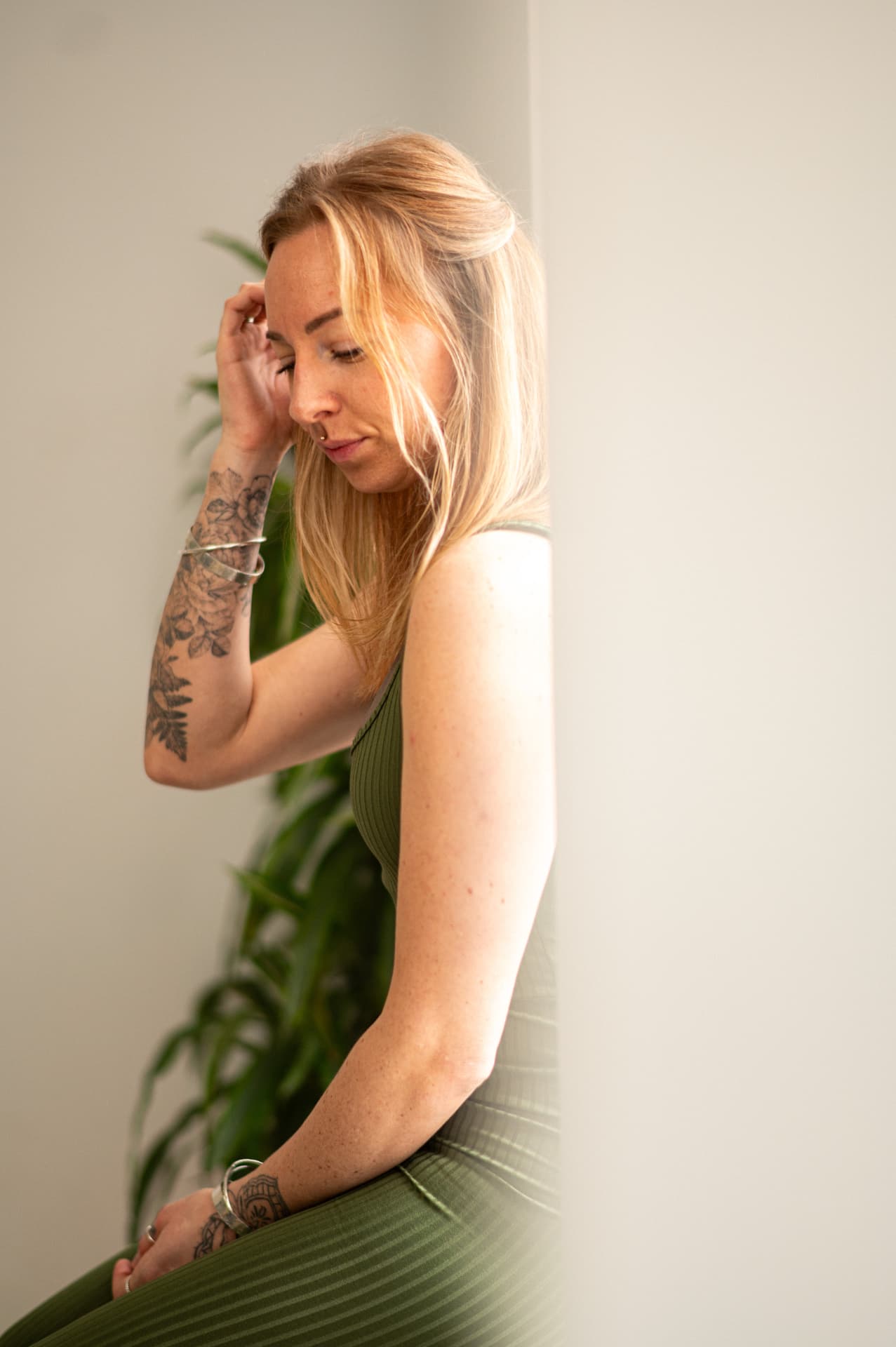 Lottie sitting cross-legged on the floor holding a mug beside candles and a plant