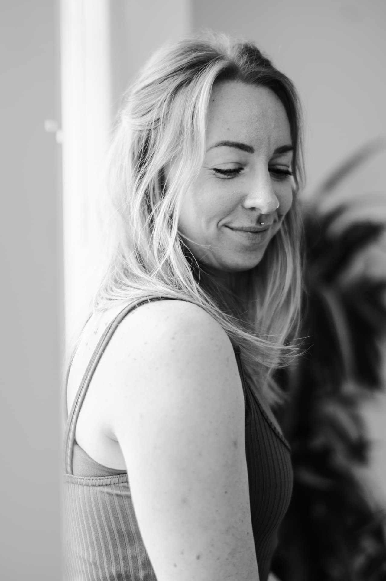 Black and white portrait of Lottie looking down with a quiet smile